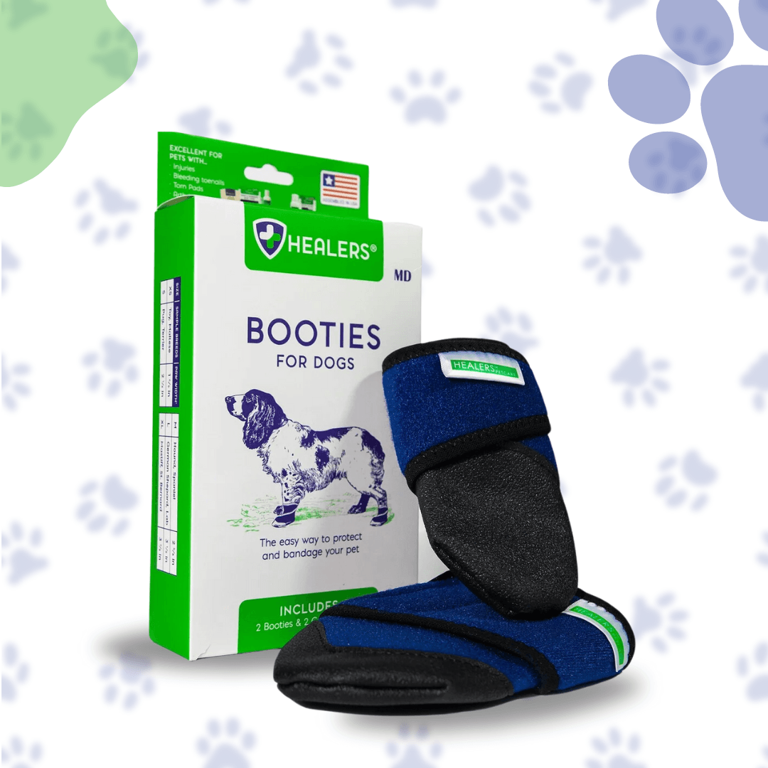 A pair of blue and black dog booties is displayed next to a white and green product box labeled 'BOOTIES FOR DOGS' with the Healers logo. The booties feature a dark blue fabric with black trim and a green stripe detail. The box shows an image of a dog and text promoting the product's benefits. The background is light with a pattern of paw prints in various shades of blue and green.
