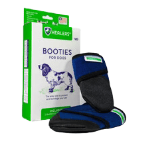 A pair of blue and black dog booties is displayed next to a white and green product box labeled 'BOOTIES FOR DOGS' with the Healers logo. The booties feature a dark blue fabric with black trim and a green stripe detail. The box shows an image of a dog and text promoting the product's benefits.