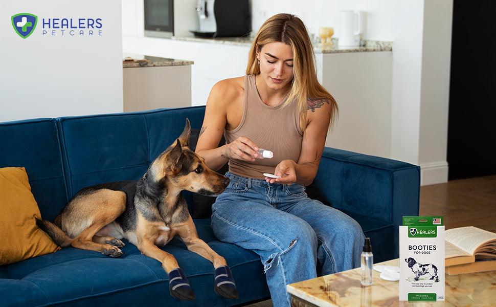 Woman applying Healers Booties for Dogs on a sitting dog, demonstrating comfortable and easy paw bandaging at home
