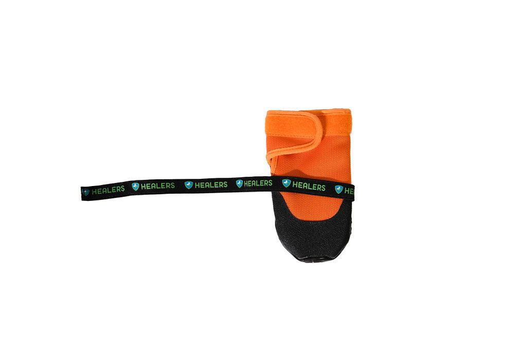 Single orange Healers dog boot with adjustable black strap partially unfastened, showing hook-and-loop closure and black textured sole